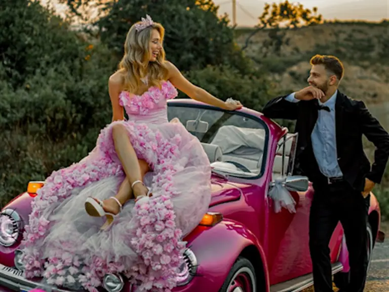 Pembe cabrio Vosvos gelin arabasının kaputunda oturan gelin ve yanında damat